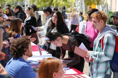 Students are asking questions and signing up for programs at an outdoor tabling event