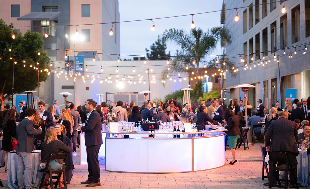 The scene at LMU Loyola Law School with twinkling lights strung overhead and tables set up with alumni and guests mingling at Grand Reunion.